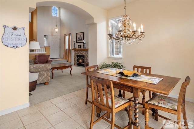 dining room with an inviting chandelier, light tile patterned floors, a healthy amount of sunlight, arched walkways, and light colored carpet