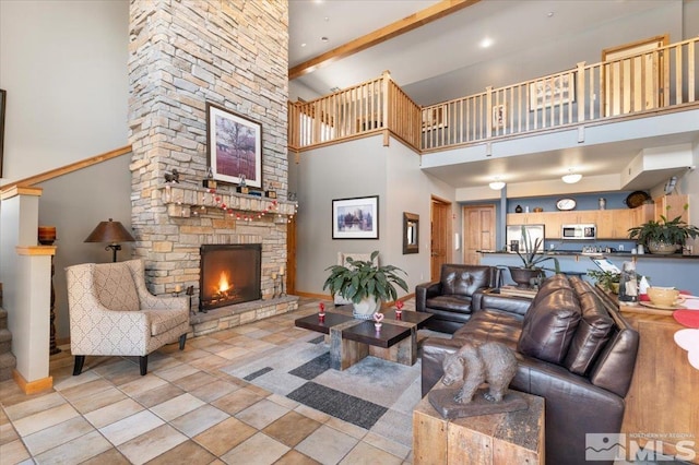 tiled living area featuring a towering ceiling, a stone fireplace, baseboards, and beam ceiling