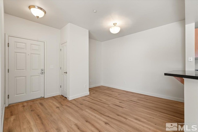 unfurnished dining area with light wood-style flooring and baseboards