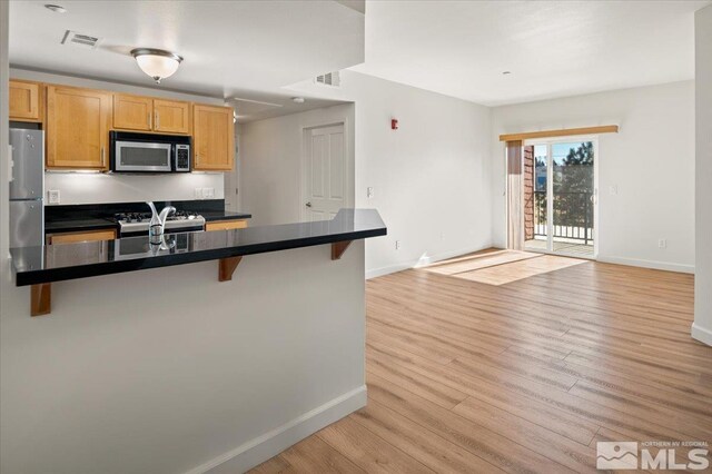 kitchen with stainless steel microwave, visible vents, a breakfast bar area, and dark countertops