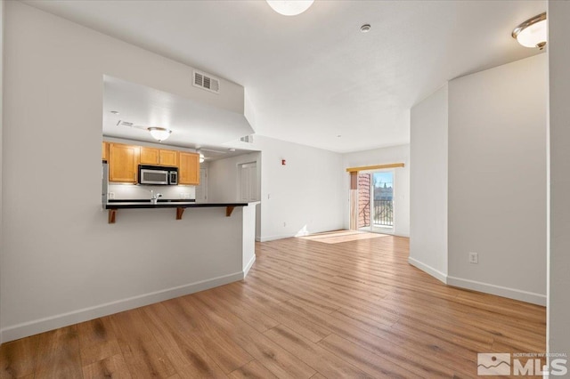 unfurnished living room with light wood-style floors, baseboards, and visible vents