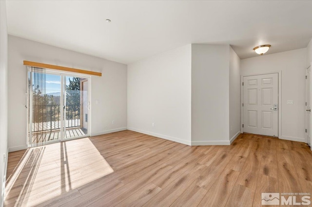 spare room with baseboards and light wood finished floors