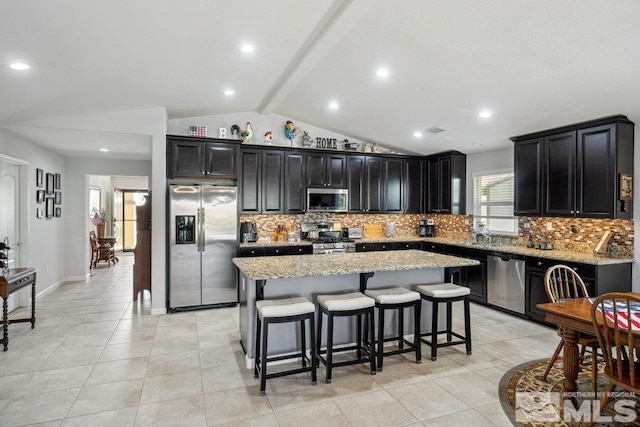 kitchen with tasteful backsplash, a kitchen island, dark cabinetry, stainless steel appliances, and vaulted ceiling with beams
