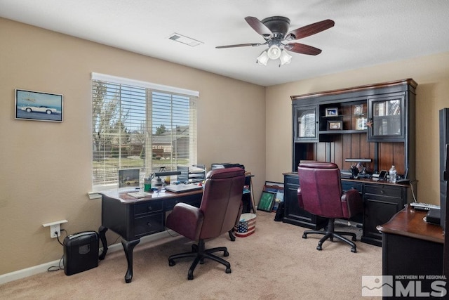 office space with visible vents, baseboards, a ceiling fan, and light carpet