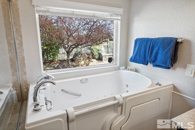 full bath with a whirlpool tub and a textured wall