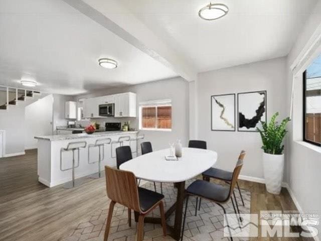 dining space featuring wood finished floors, baseboards, and stairs