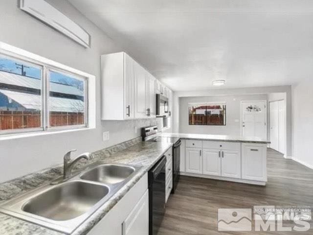 kitchen featuring stainless steel microwave, a peninsula, black dishwasher, range with electric stovetop, and a sink