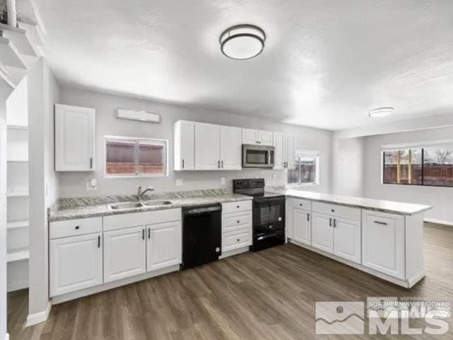 kitchen featuring a peninsula, light countertops, black appliances, dark wood-type flooring, and a sink