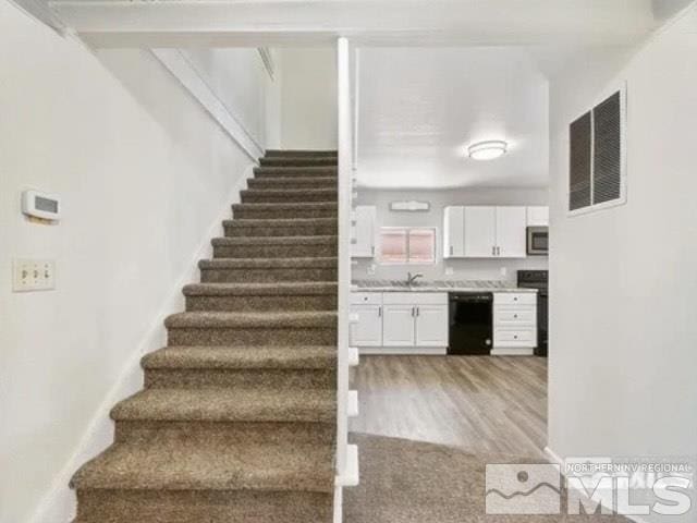 stairway featuring visible vents and wood finished floors