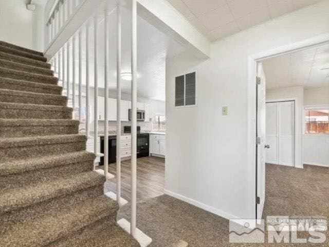 stairs with carpet floors, baseboards, and visible vents