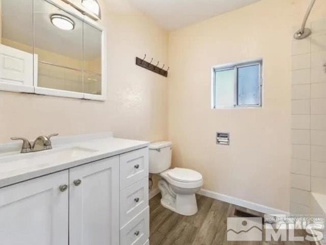 full bath with toilet, wood finished floors, and vanity
