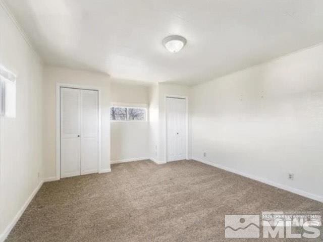 unfurnished bedroom featuring baseboards, carpet, and multiple closets