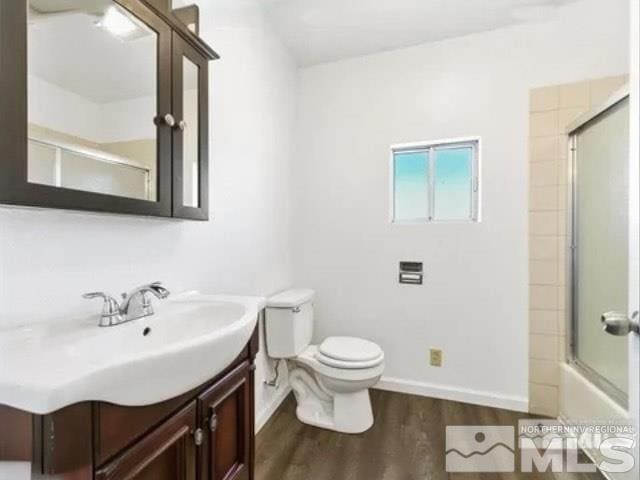 full bathroom featuring baseboards, bath / shower combo with glass door, toilet, vanity, and wood finished floors