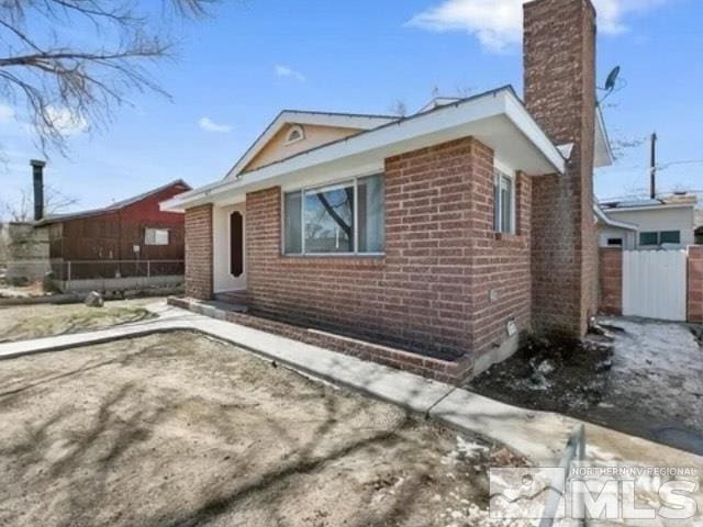 ranch-style house featuring fence, brick siding, and a chimney