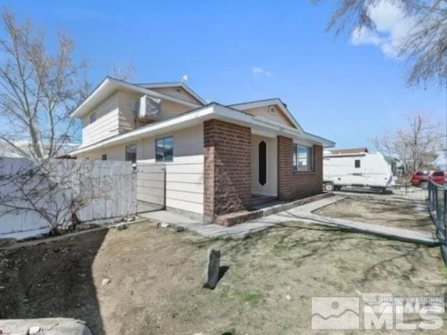 view of property exterior featuring brick siding and fence