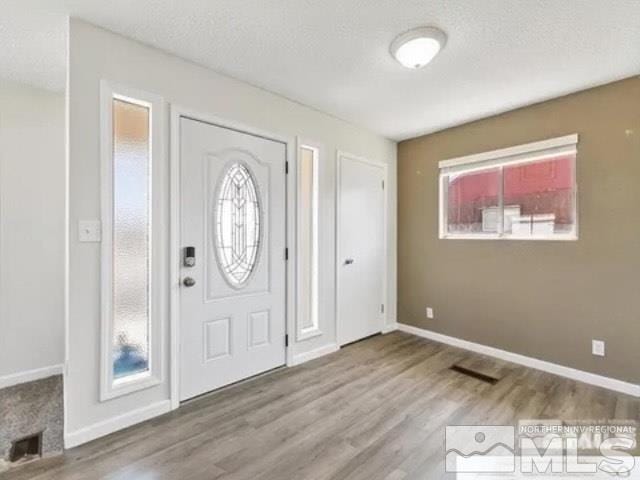 entryway with visible vents, baseboards, and wood finished floors