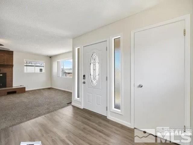 foyer with a fireplace, baseboards, a textured ceiling, and wood finished floors
