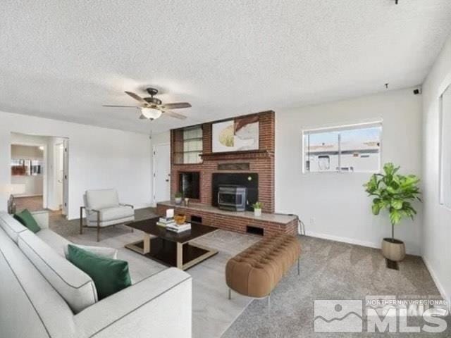 living area with carpet floors, ceiling fan, baseboards, and a textured ceiling