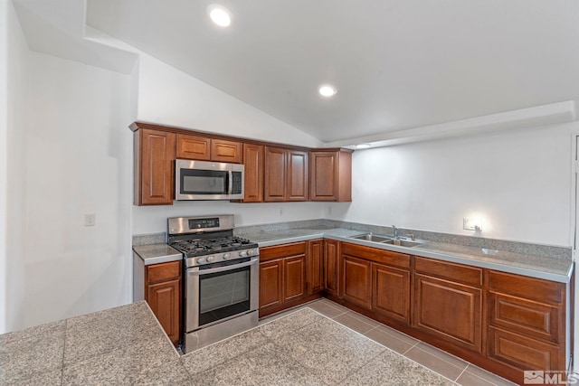 kitchen with a sink, brown cabinets, appliances with stainless steel finishes, and lofted ceiling