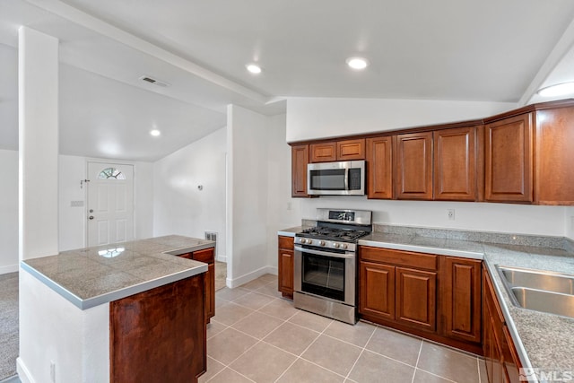 kitchen with visible vents, brown cabinetry, lofted ceiling, tile countertops, and appliances with stainless steel finishes