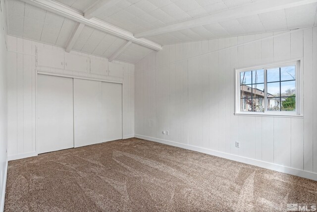 unfurnished bedroom with a closet, baseboards, carpet, and lofted ceiling with beams
