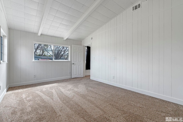 empty room with baseboards, lofted ceiling with beams, carpet flooring, wooden walls, and visible vents