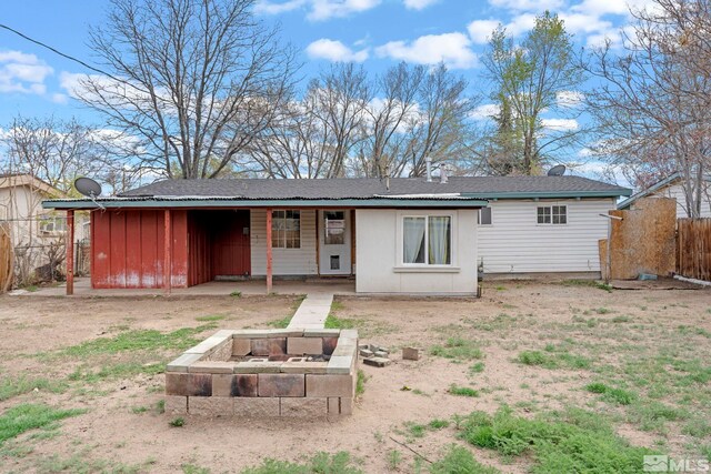 back of property with a fire pit and fence