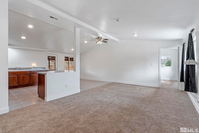 unfurnished living room with a ceiling fan, visible vents, light carpet, a sink, and vaulted ceiling with beams