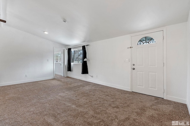 foyer entrance featuring carpet flooring, baseboards, and lofted ceiling