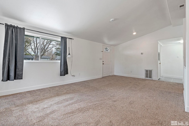 empty room featuring visible vents, baseboards, carpet, and lofted ceiling