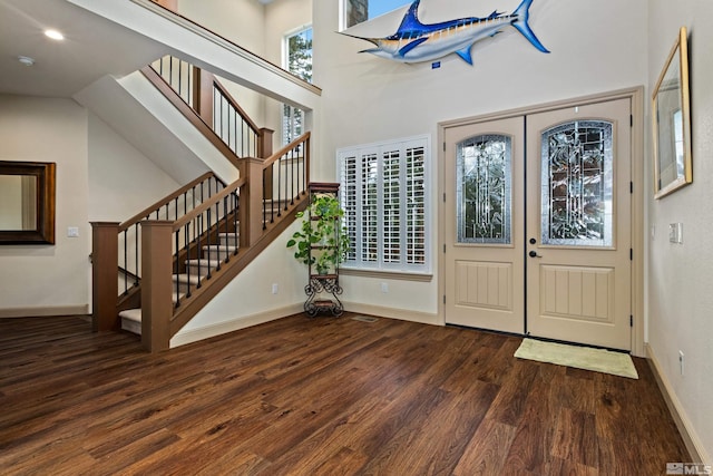 foyer entrance with a healthy amount of sunlight, stairs, baseboards, and wood finished floors