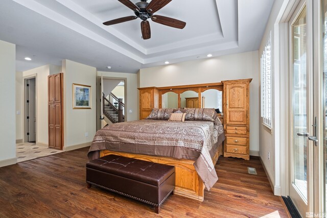 bedroom with recessed lighting, baseboards, wood finished floors, and a raised ceiling
