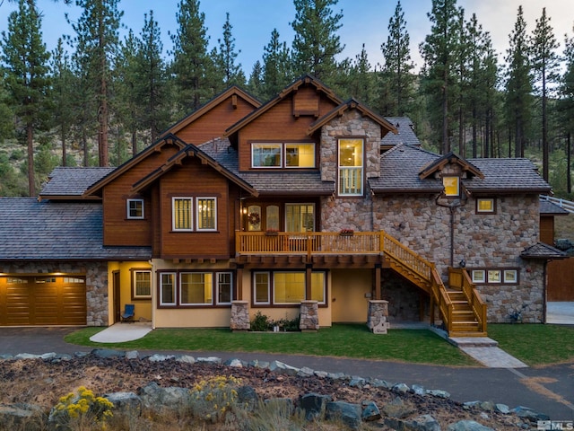 view of front of house featuring a front yard, stone siding, a garage, stairway, and driveway