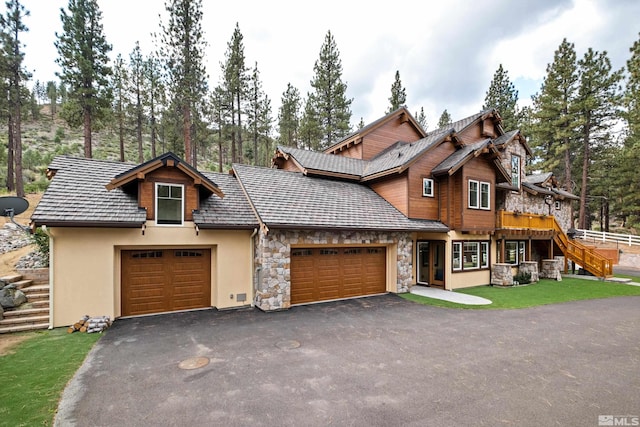 view of front of home with an attached garage, stone siding, aphalt driveway, stucco siding, and stairs