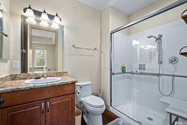 full bathroom with a shower stall, vanity, toilet, and a textured wall