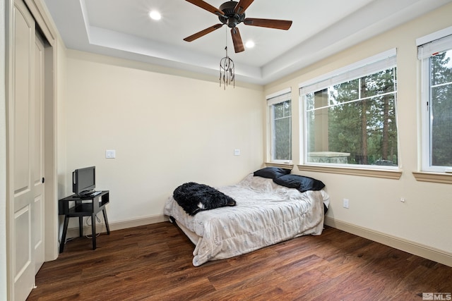 bedroom with a raised ceiling, wood finished floors, and baseboards