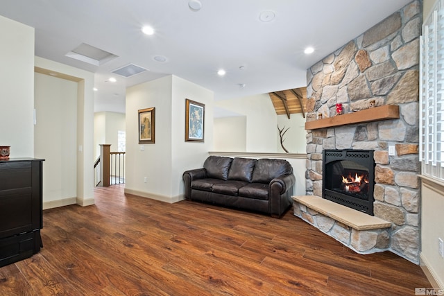 living room featuring a stone fireplace, baseboards, recessed lighting, and wood finished floors