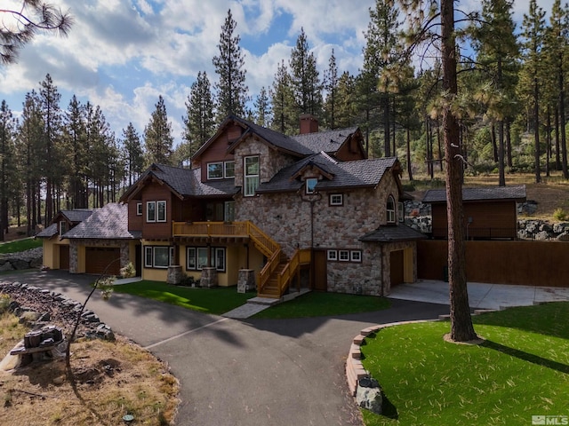 view of front facade featuring aphalt driveway, stairway, stone siding, a front lawn, and a chimney