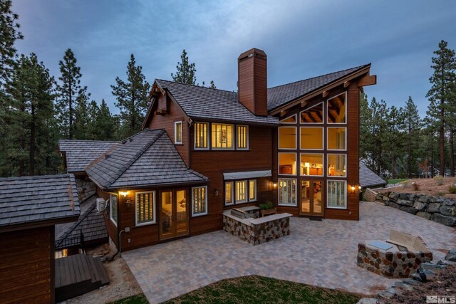 rear view of property featuring a patio area, french doors, a fire pit, and a chimney