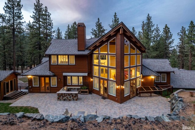 back of property featuring an outdoor fire pit, a chimney, and a patio area