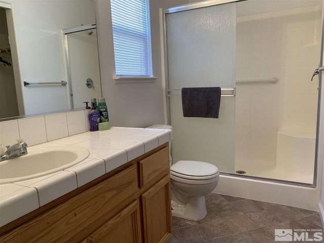 bathroom with toilet, a stall shower, and vanity