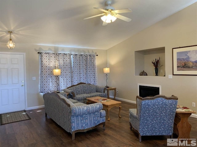 living area featuring wood finished floors, baseboards, a ceiling fan, and vaulted ceiling