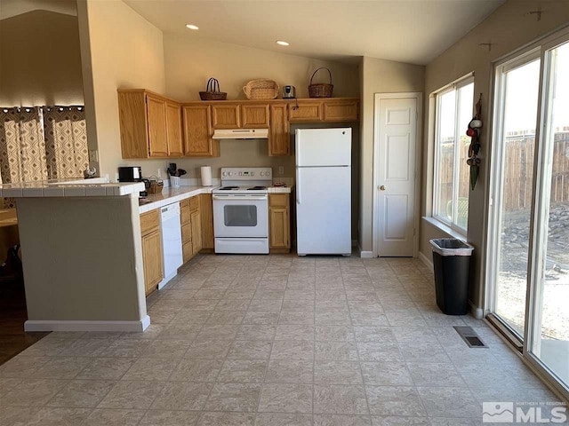 kitchen with tile counters, white appliances, plenty of natural light, and lofted ceiling