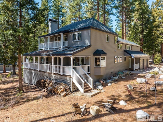 back of property featuring a porch, a balcony, a chimney, and an attached garage