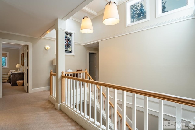 hallway featuring ornamental molding, baseboards, an upstairs landing, and light carpet