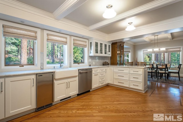 kitchen featuring a peninsula, dishwasher, light countertops, and a sink