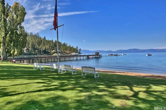 dock area with a water and mountain view and a lawn