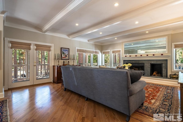 living area featuring french doors, crown molding, a fireplace with raised hearth, beamed ceiling, and wood finished floors
