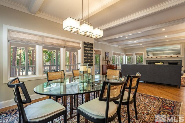 dining room with crown molding, beam ceiling, plenty of natural light, and wood finished floors