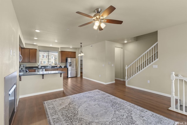kitchen with a ceiling fan, a peninsula, dark wood-style floors, and stainless steel appliances